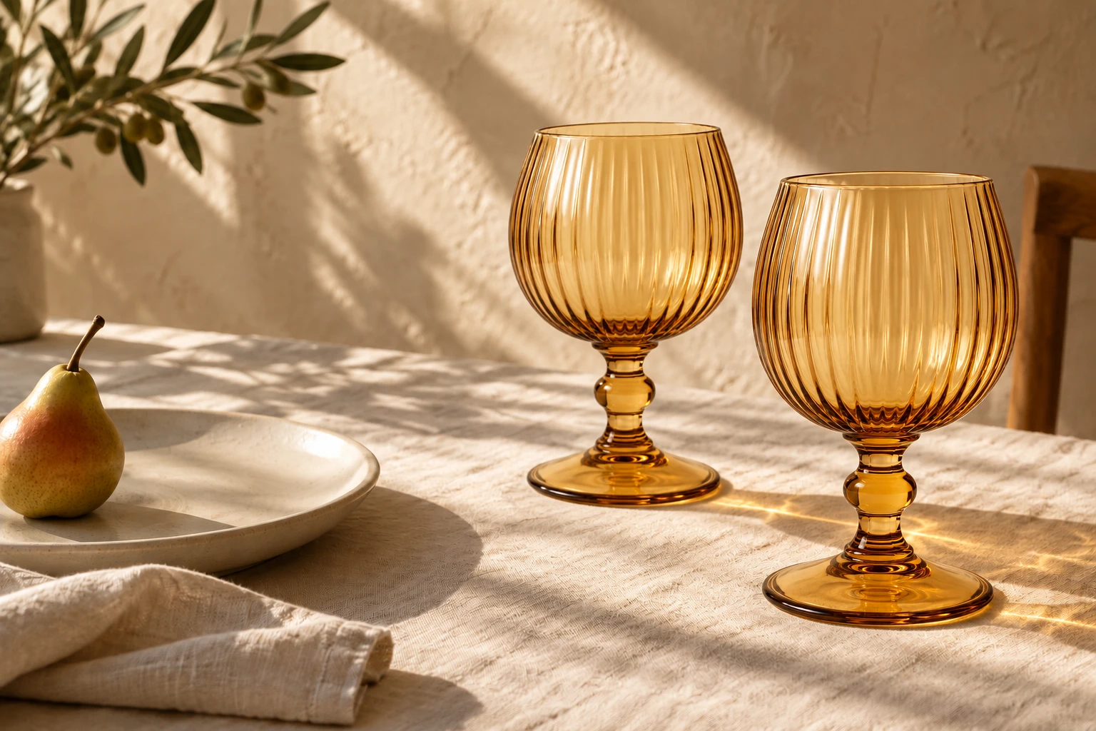 Honey amber fluted goblets on an ivory linen dining table in warm light